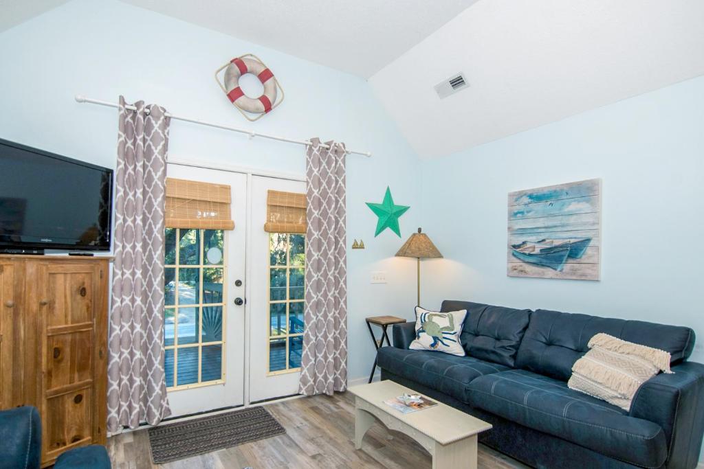 a living room with a blue couch and a tv at Geechee Girl in Edisto Beach