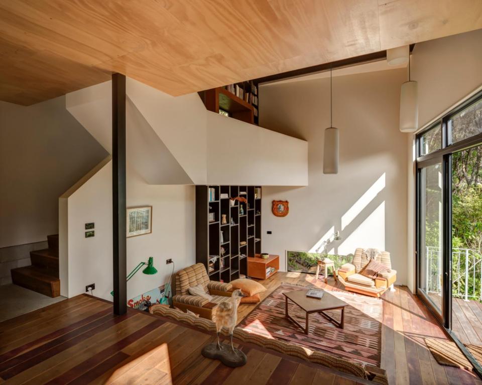 a living room with a vaulted ceiling and a large window at Blackpool House in Oneroa