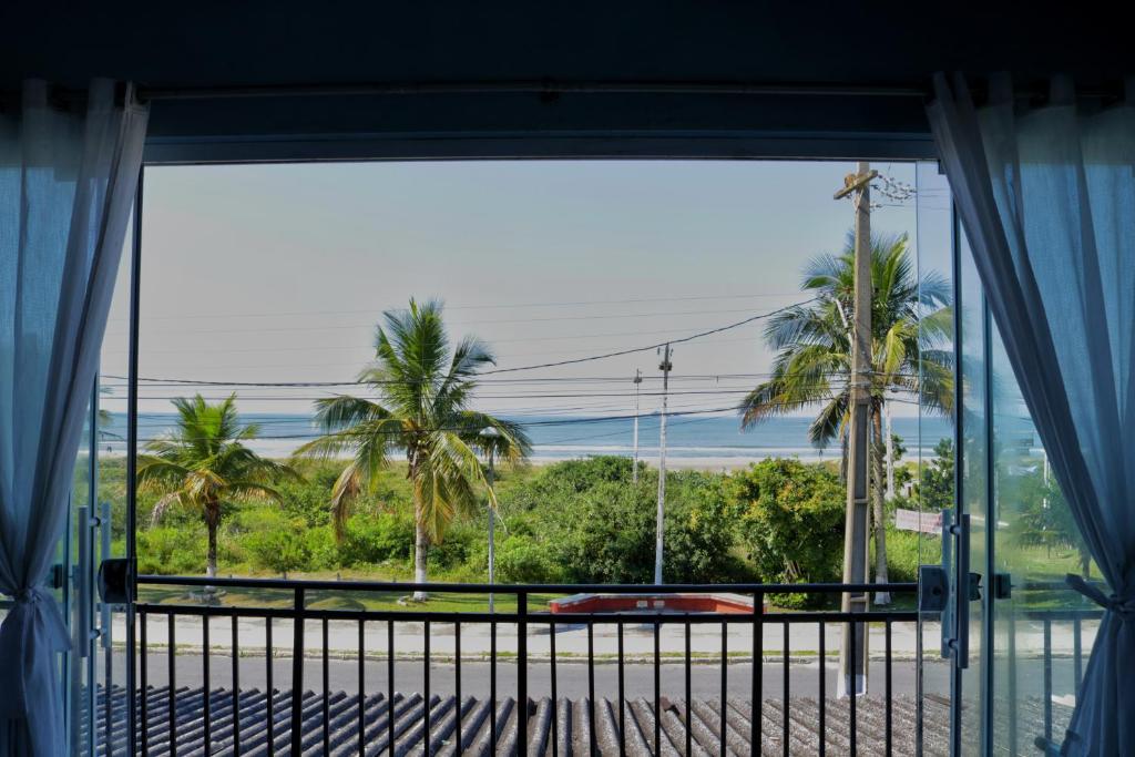 una ventana con vistas al océano y a las palmeras en Apto Frente para o Mar, en Pontal do Paraná