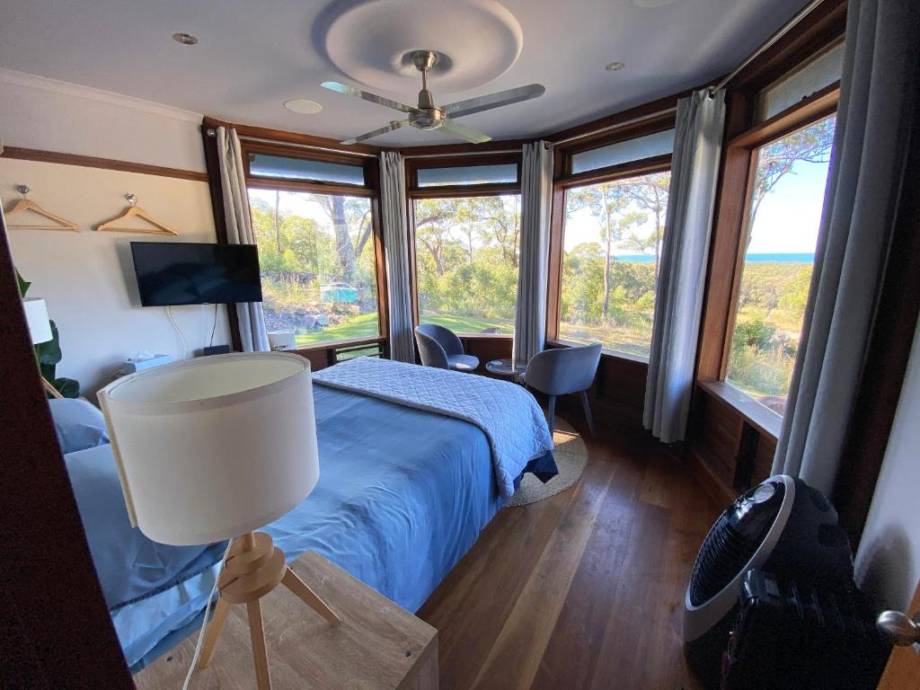 新月岬The Pool House - Crescent Head - stunning ocean views, pet friendly的一间卧室配有一张床、一盏灯和窗户