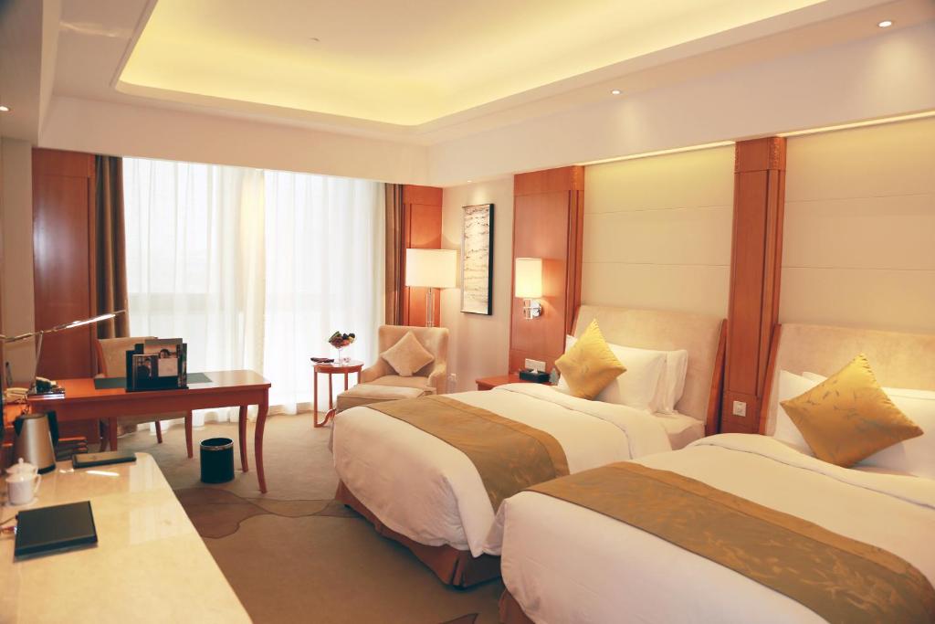a hotel room with two beds and a desk at Huaguoshan Hotel in Lianyungang