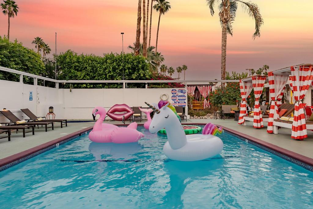 einem Pool mit zwei aufblasbaren Flamingos im Wasser in der Unterkunft Float Palm Springs - Adults Only in Palm Springs