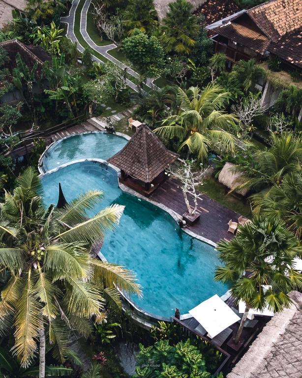 an overhead view of a swimming pool with palm trees at Keramas Sacred River Retreat Resort and Villa in Keramas