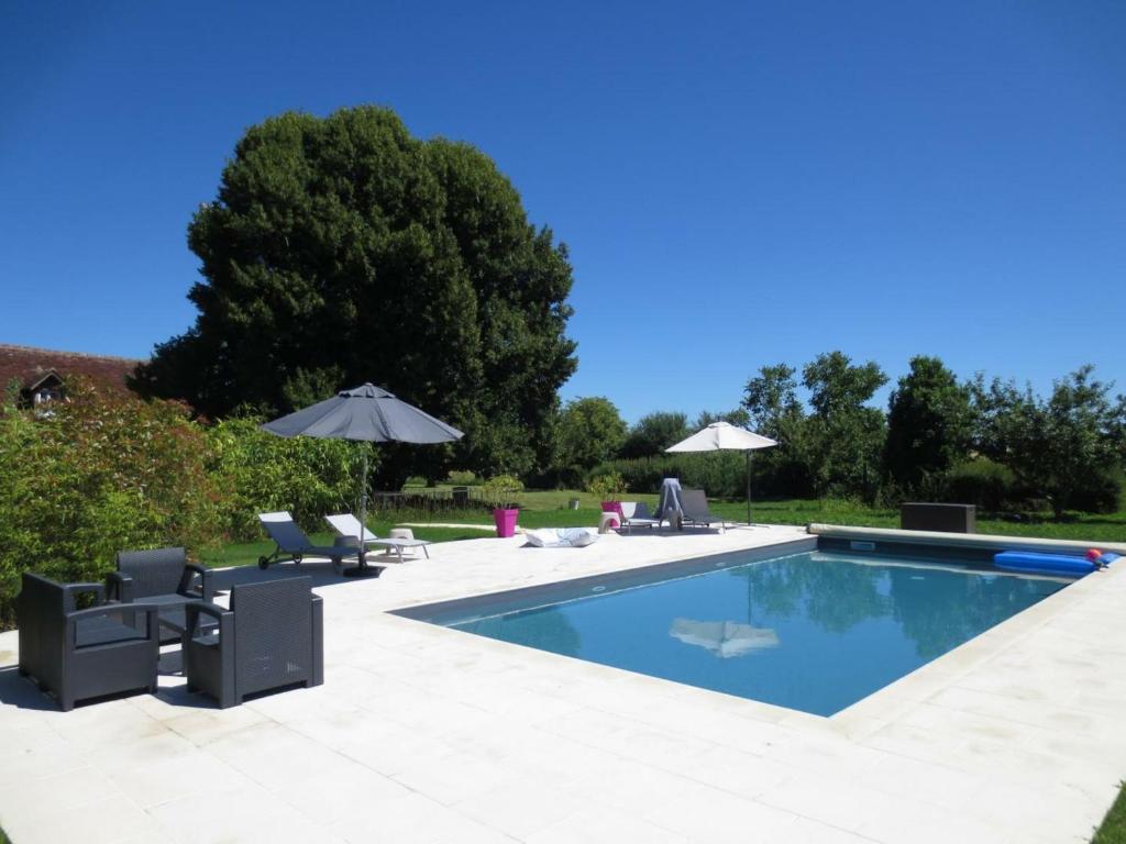 una piscina con sillas y sombrillas en un patio en Gîte Nazelles-Négron, 3 pièces, 3 personnes - FR-1-381-7, en Montreuil-en-Touraine