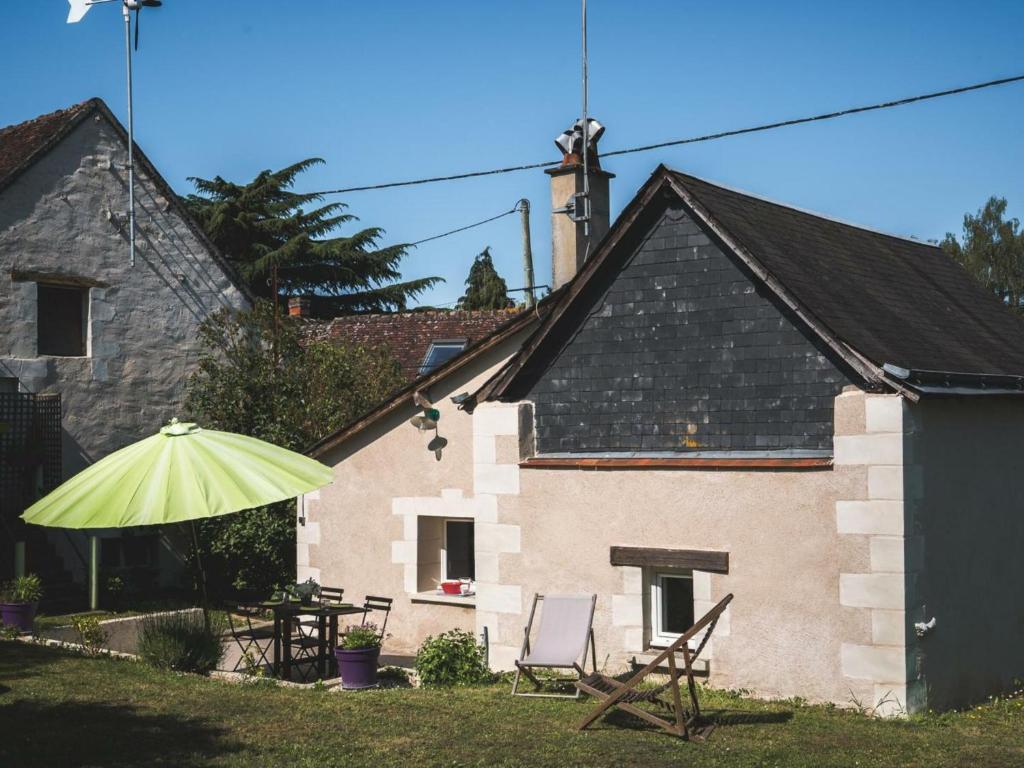 謝爾河畔阿瑟的住宿－Gîte Athée-sur-Cher, 2 pièces, 2 personnes - FR-1-381-371，院子里有两把椅子和一把伞的房子