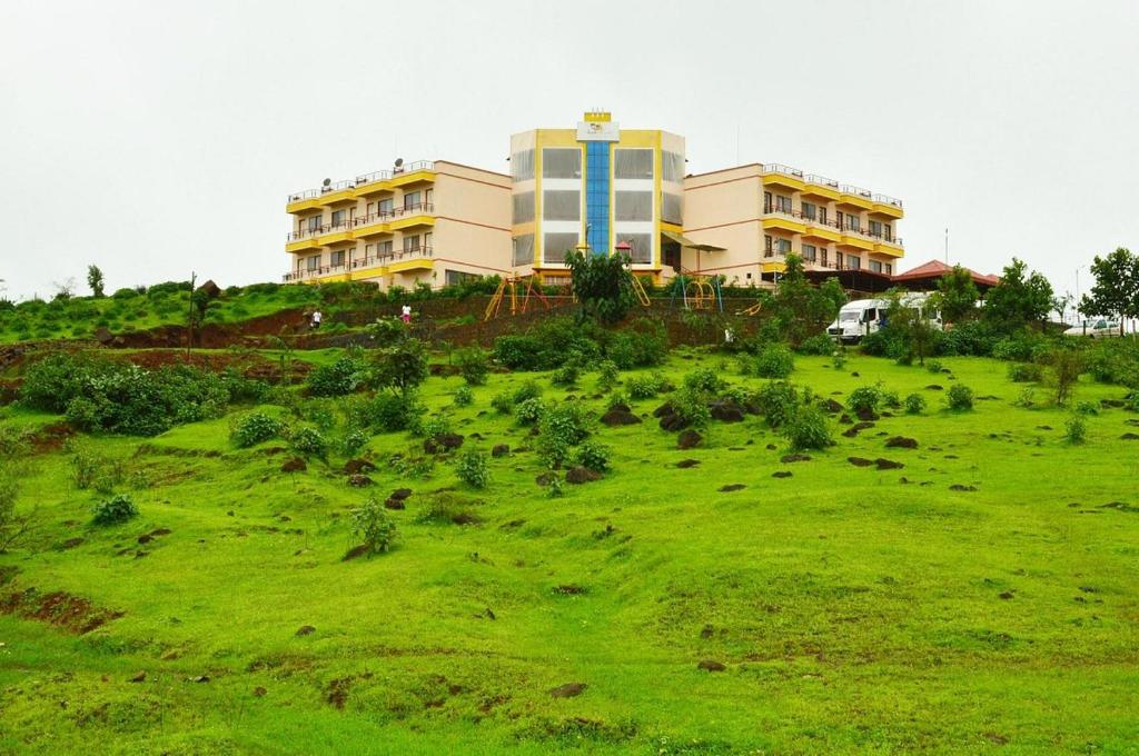een gebouw op een groen veld met dieren bij SS Resort Near Jaysagar Lake in Jawhār