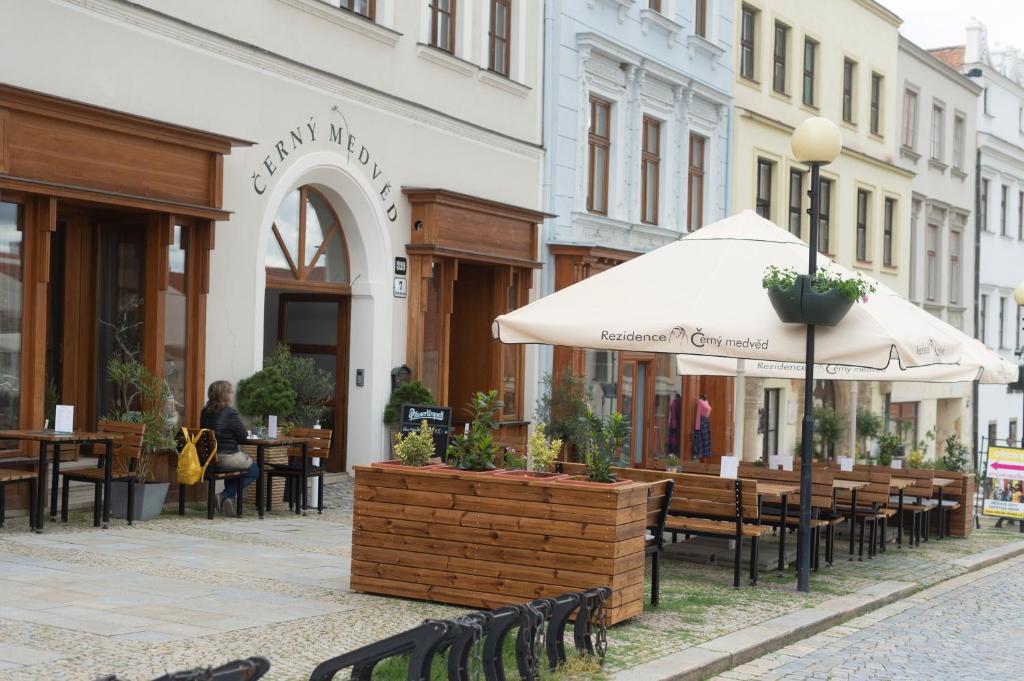 un patio con mesas, sillas y una sombrilla en Rezidence Černý medvěd en Znojmo