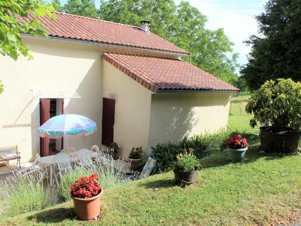 une maison avec une table, des chaises et un parasol dans l'établissement Gîte Mensignac, 3 pièces, 5 personnes - FR-1-616-40, à Mensignac