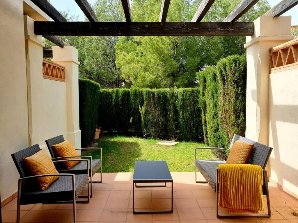 um pátio com cadeiras, uma mesa e um jardim em Adosado Los Olivos, Sierra Cortina em Finestrat