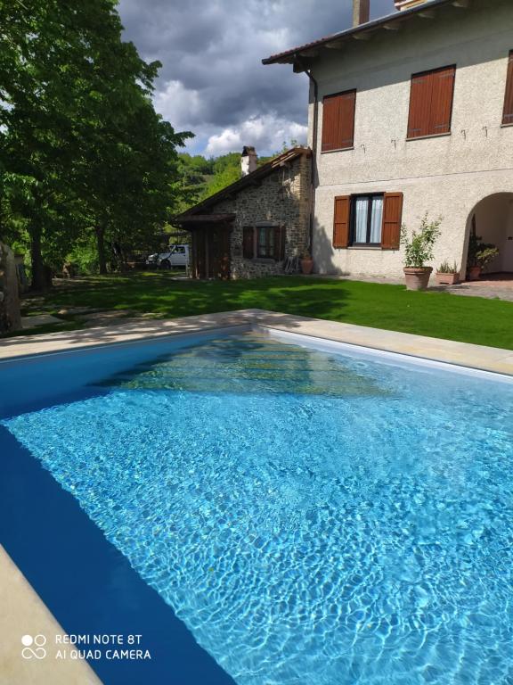 a blue swimming pool in front of a house at Casa Renacci in Subbiano