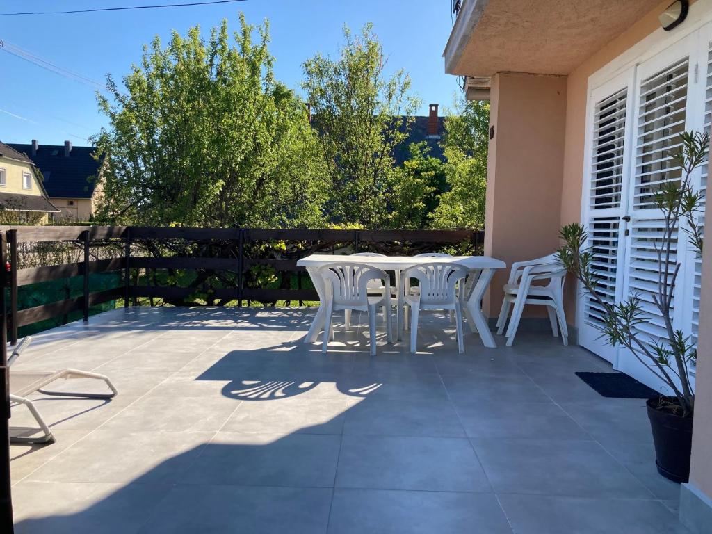 eine Terrasse mit 2 Tischen und weißen Stühlen darauf in der Unterkunft Bogi House in Balatonfüred