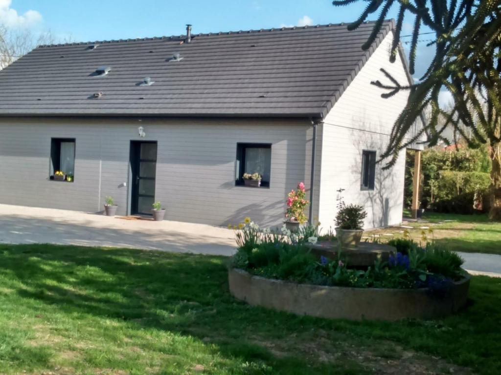 uma casa branca com uma garagem com flores num quintal em Gîte Saint-Martin-d'Écublei, 4 pièces, 6 personnes - FR-1-497-23 em Saint-Martin-dʼÉcublei