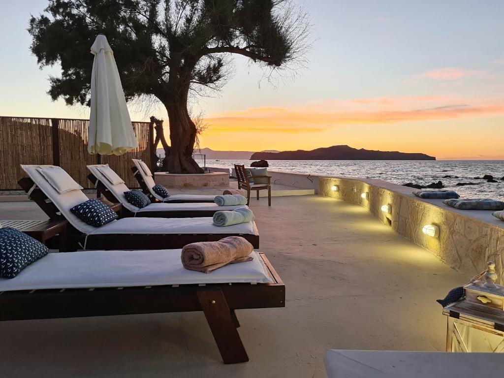 a row of chaise lounges on the beach at sunset at Seastar seafront villa in Kalamaki