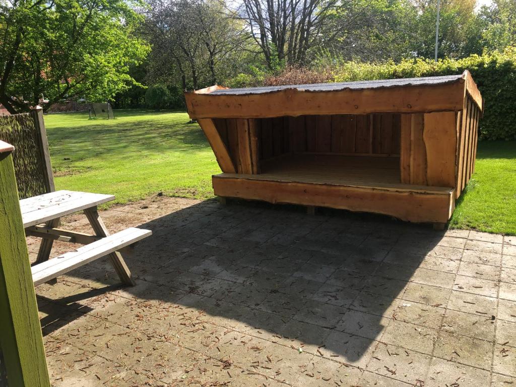 una casa de perros de madera sentada junto a un banco en Familiehuis Boysen Shelters, en Ribe