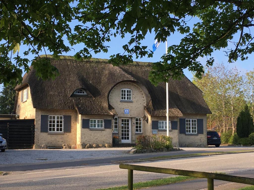 a building with a thatched roof on a street at Danhostel Rebild in Skorping