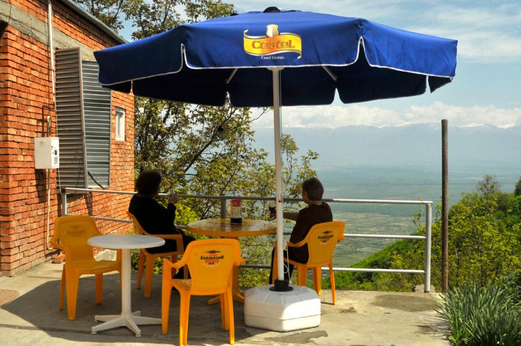 two people sitting at a table under an umbrella at Maya Guest House in Sighnaghi
