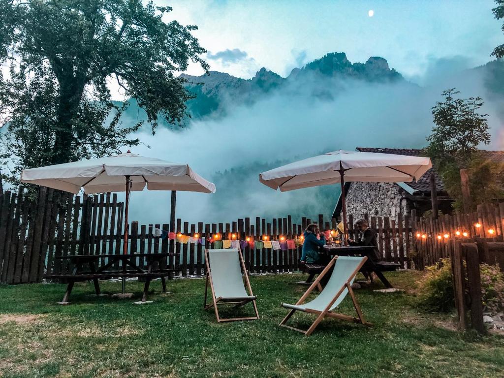 zwei Tische und Stühle mit Sonnenschirmen im Gras in der Unterkunft Visaisa taverna & foresteria in Acceglio