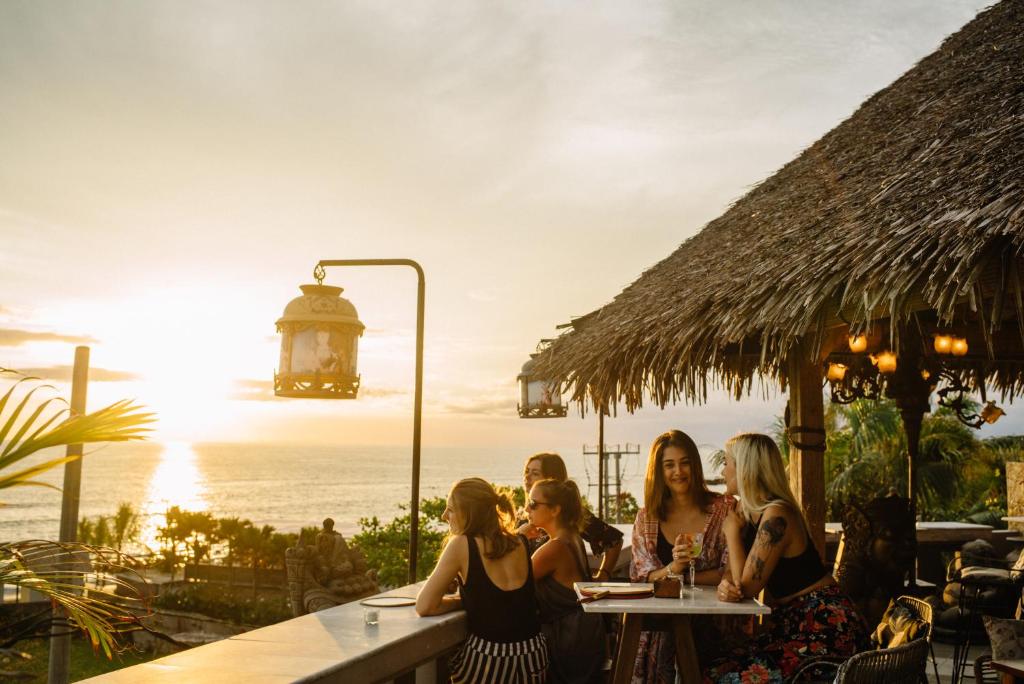 a group of women sitting at a table with the ocean in the background at Hotel Tugu Bali - CHSE Certified in Canggu