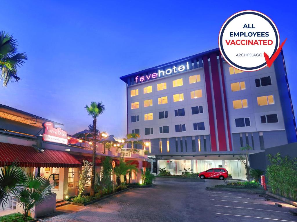 favehotel Sudirman Bojonegoro في Bojonegoro: فندق تقف امامه سيارة حمراء