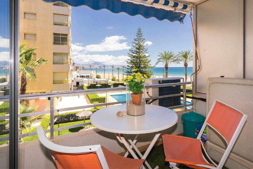 einen Tisch und Stühle auf einem Balkon mit Meerblick in der Unterkunft Primera Linea Playa San Juan in El Campello