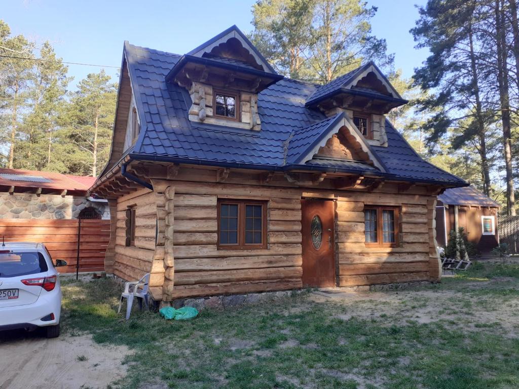 a log cabin with a car parked in front of it at Domek Letniskowy - M & E in Warchały