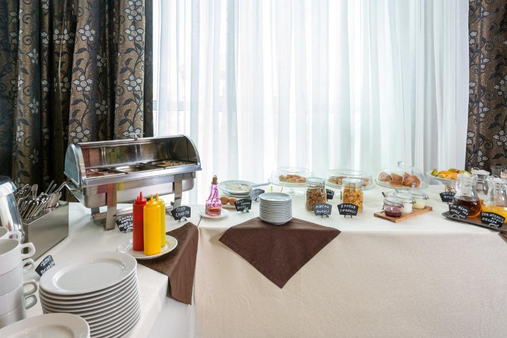 a table with plates of food on a table with a window at Business Hotel Diplomat in Nizhny Novgorod