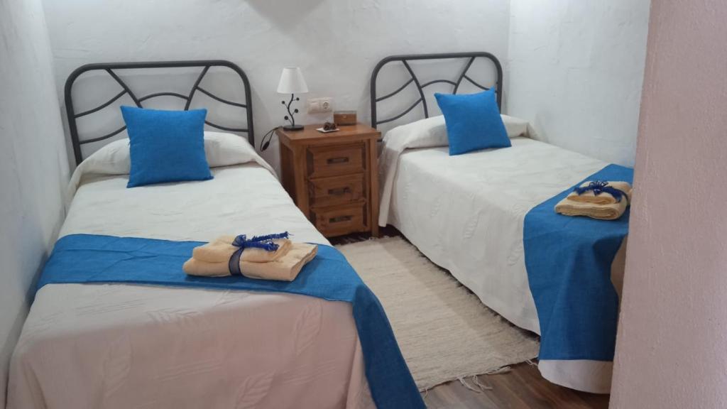 1 dormitorio con 2 camas y almohadas azules en Casa Osciris, en El Cercado