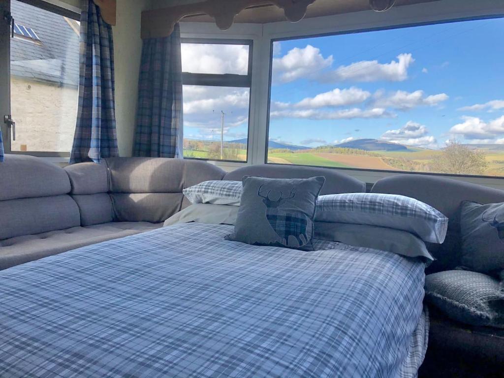 um quarto com uma cama e uma grande janela em Lettoch Farm Holiday Home em Dufftown