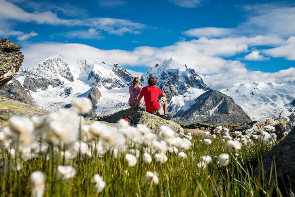 a couple sitting on a rock in front of a mountain at Crystal Hotel superior in St. Moritz