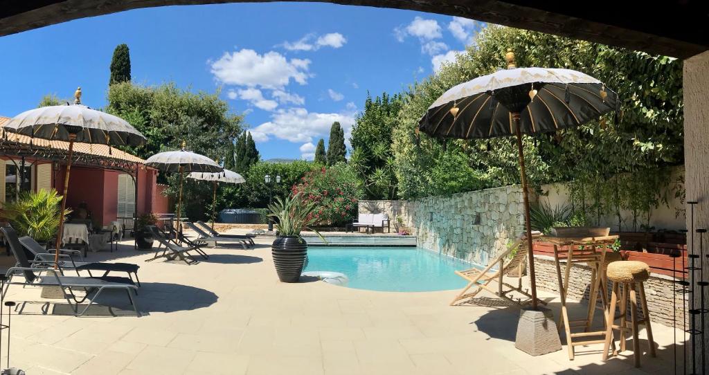 una piscina con sombrillas y sillas y una piscina en VILLA MATHIS, en Mouans-Sartoux
