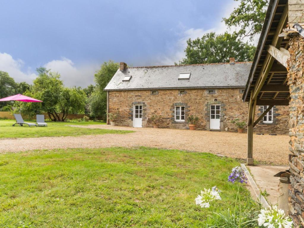 uma casa de pedra com um guarda-chuva rosa no quintal em Gîte Guémené-Penfao, 3 pièces, 4 personnes - FR-1-306-875 em Guéméné-Penfao