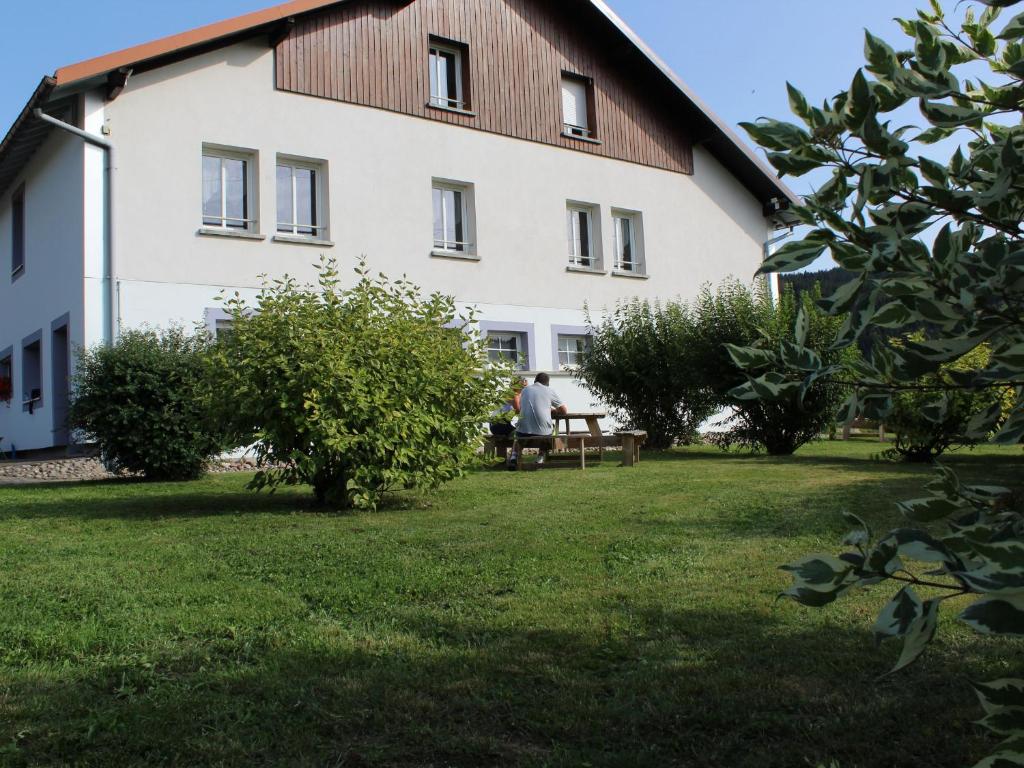 Ein Mann, der vor einem Gebäude auf einer Bank sitzt. in der Unterkunft Gîte Gérardmer, 3 pièces, 4 personnes - FR-1-589-124 in Gérardmer