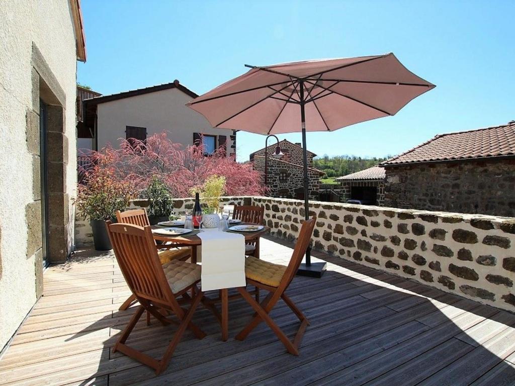 a table and chairs with an umbrella on a deck at Gîte Polignac, 3 pièces, 4 personnes - FR-1-582-58 in Polignac