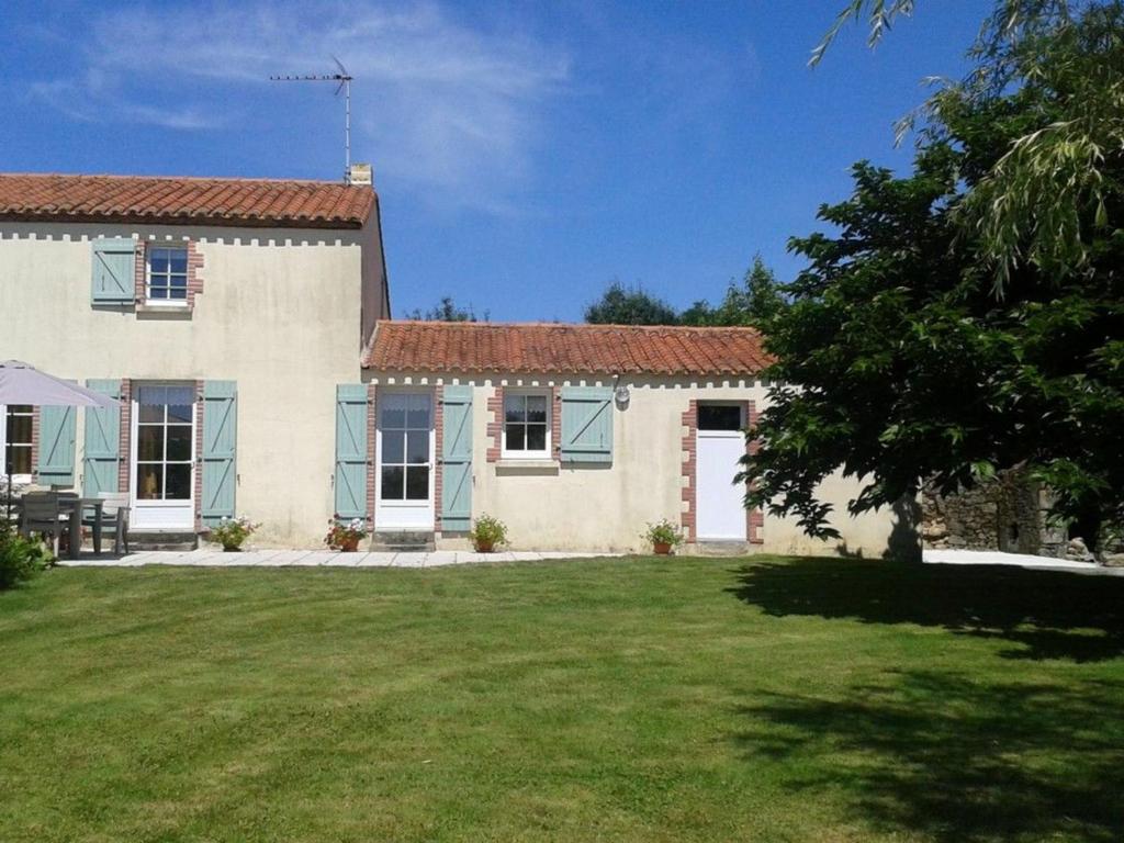 une maison blanche avec des fenêtres bleues et une cour dans l'établissement Gîte Saint-Martin-des-Tilleuls, 4 pièces, 6 personnes - FR-1-426-335, à Saint-Martin-des-Tilleuls