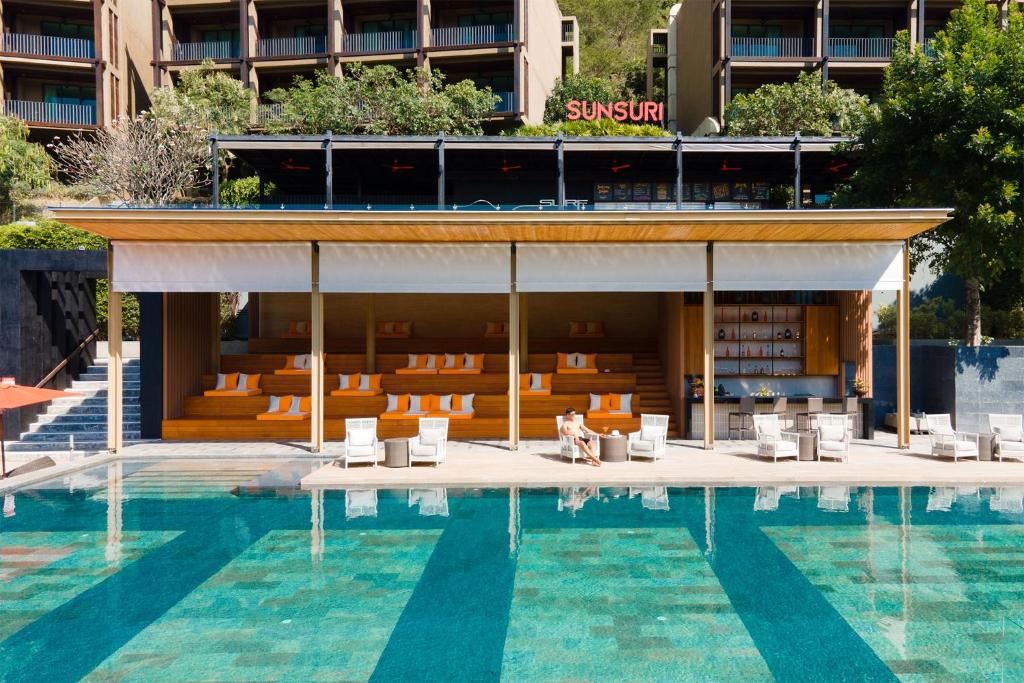 a person sitting next to a pool at a hotel at Sunsuri Phuket - SHA Plus in Nai Harn Beach