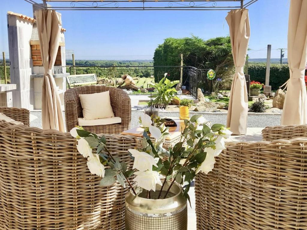 d'une terrasse avec des chaises en osier et une table fleurie. dans l'établissement Gîte Brem, 5 pièces, 8 personnes - FR-1-426-103, à Brem-sur-Mer