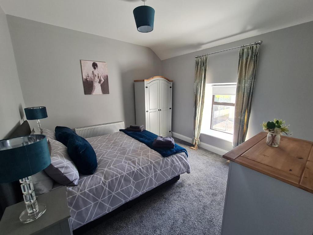 a bedroom with a bed with blue pillows and a window at AMY'S Place Charming 3 Bed House Donegal in Donegal