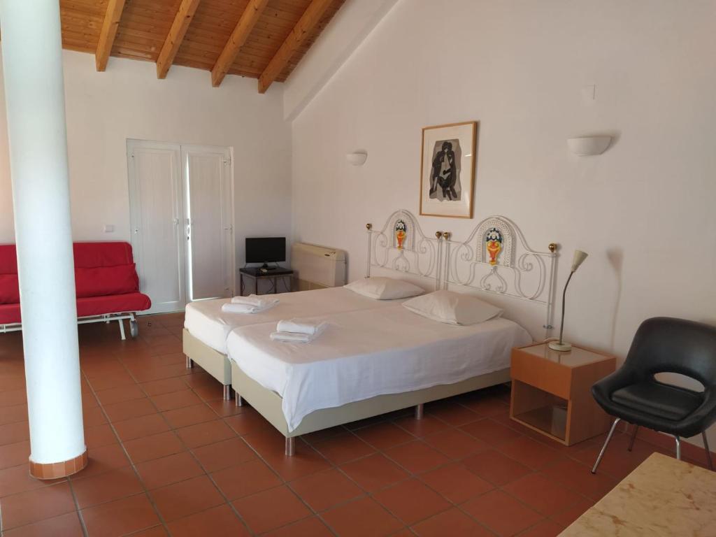 a bedroom with a white bed and a red chair at Casa da Osga in Tavira