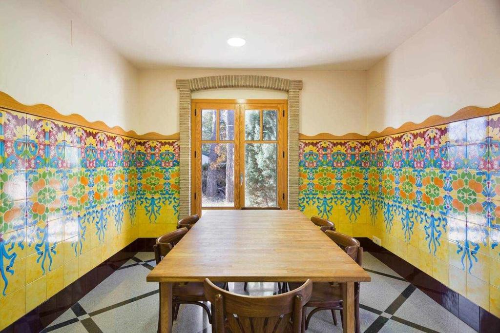 Xalet de la Muntanya El BrucMontserrat في البروك: غرفة طعام مع طاولة خشبية وورق جدران ملون