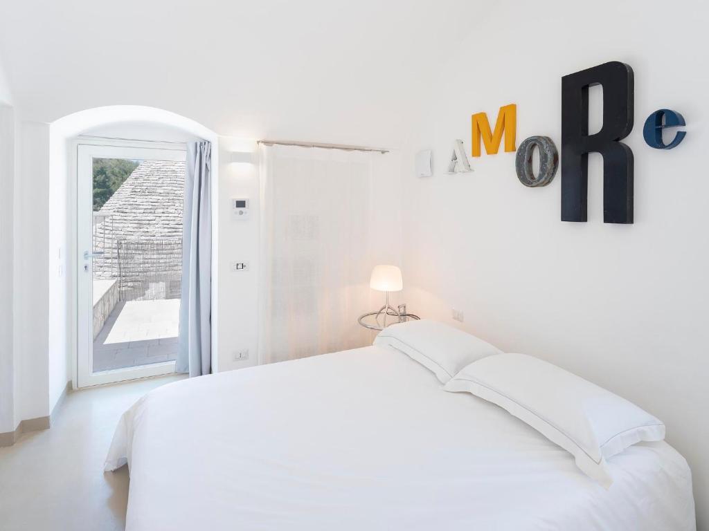 a white bedroom with a bed and a window at Lamia Alchimia in Selva di Fasano