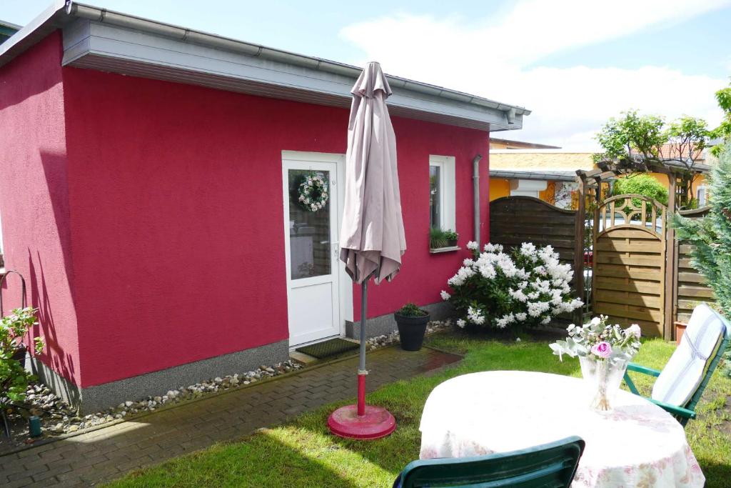 ein rosafarbenes Haus mit einem Tisch und einem Regenschirm in der Unterkunft Ferienappartement Grund in Ahlbeck