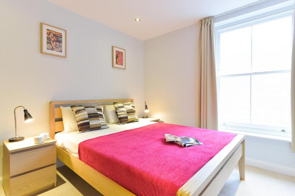 una camera da letto con un grande letto con una coperta rossa di Liverpool Street City Living a Londra