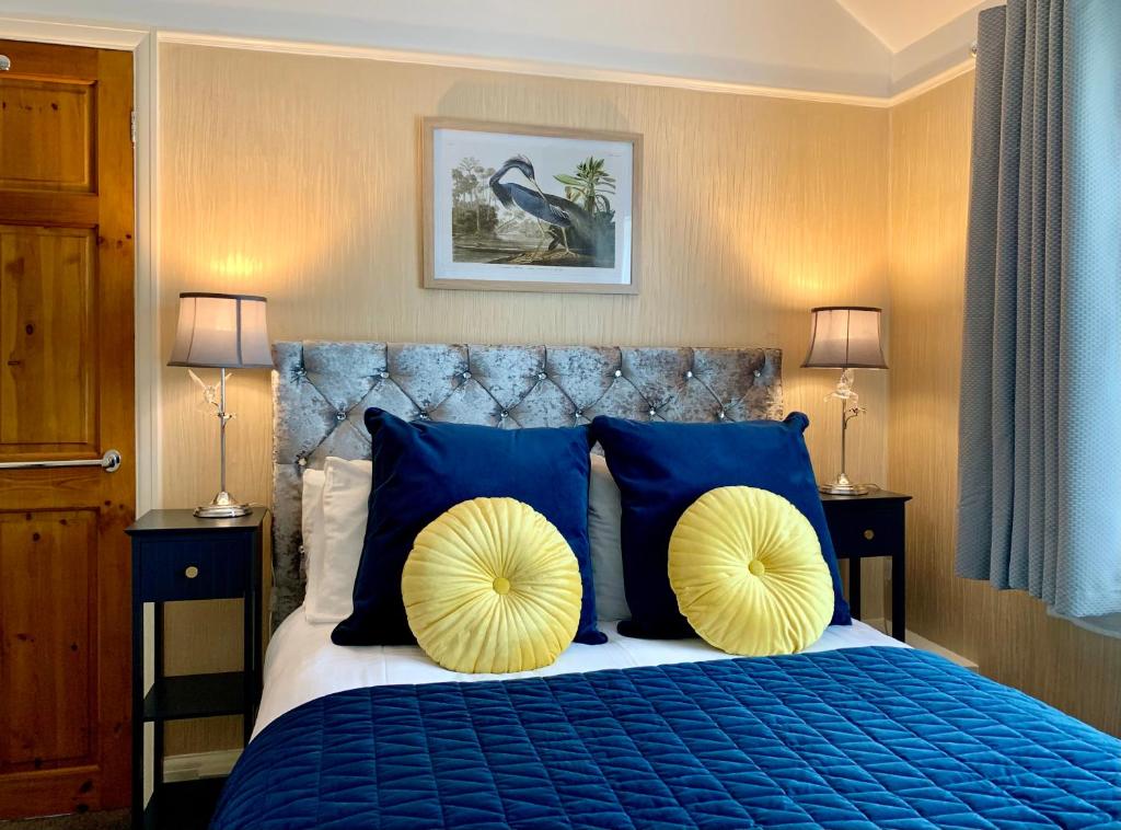 a bedroom with a blue bed with blue and yellow pillows at SW Bed & Breakfast in Swindon