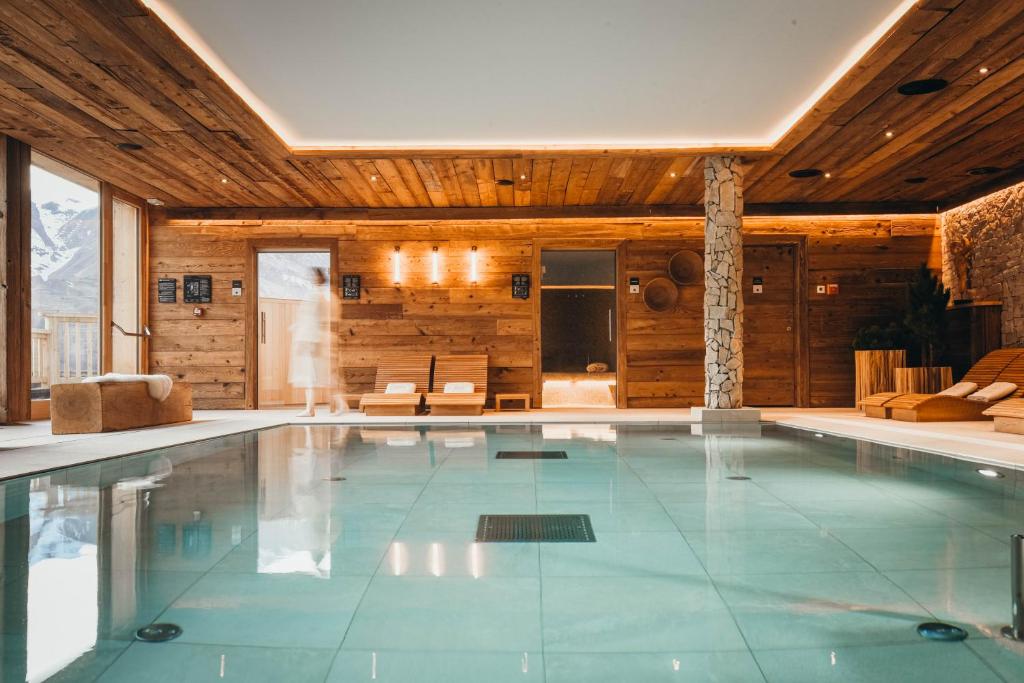 een groot zwembad in een kamer met houten wanden bij Lodji Hotel & Résidence in Saint-Martin-de-Belleville