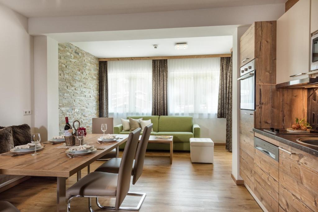 cocina y sala de estar con mesa de madera y sillas en das Burghard, en Altenmarkt im Pongau