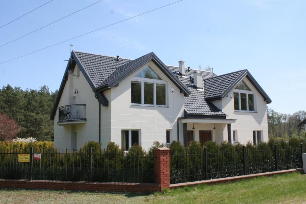 uma casa branca com um telhado preto em Uroki Natury em Lucień