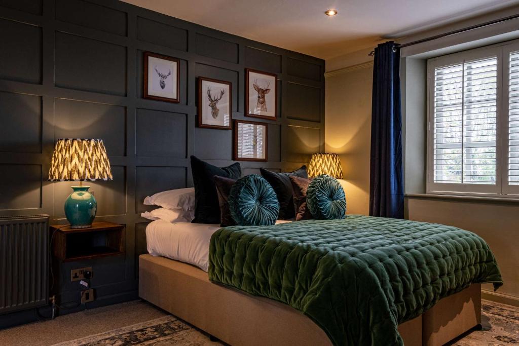 1 dormitorio con 1 cama con manta verde en The Bell & Stuart House en Stow on the Wold