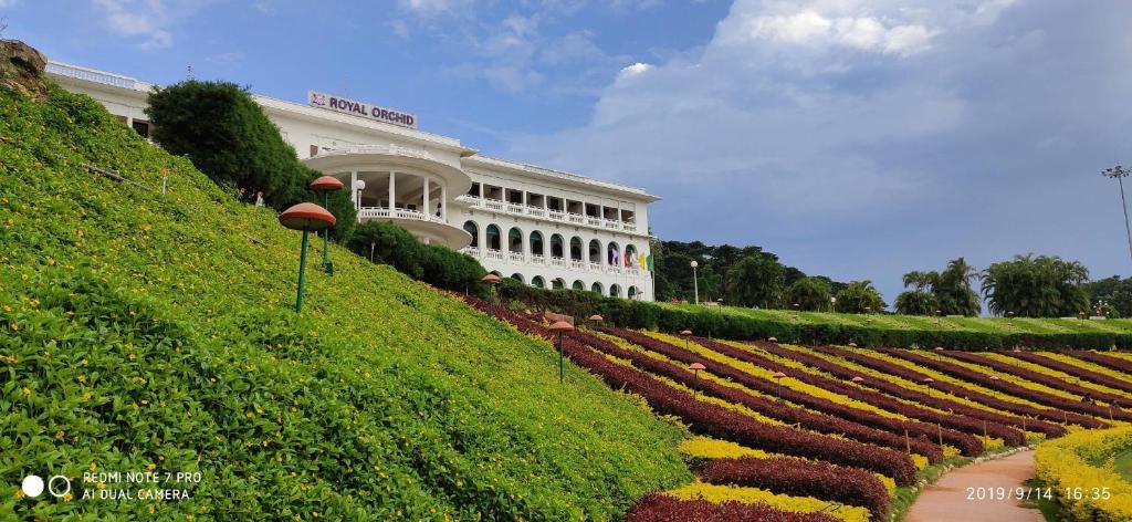 un gran edificio con un jardín delante de él en Royal Orchid Brindavan Garden Mysore, en Belagula