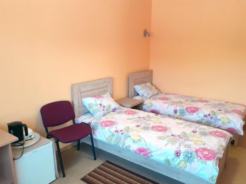 um quarto com 2 camas e uma cadeira vermelha em Kambarių nuoma - Neveronys SAURIDA em Neveronys