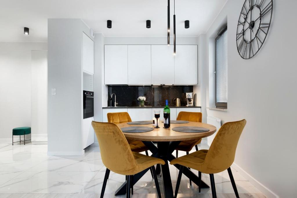 a kitchen and dining room with a wooden table and chairs at Elite Apartments Garden Gates Premium in Gdańsk